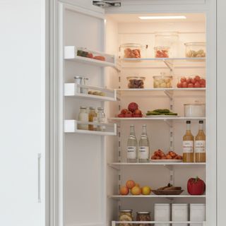 A white panel-ready built-in column refrigerator standing open in a bright kitchen