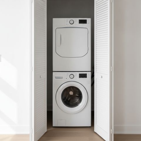A laundry closet in a condo hallway, its louvered doors open on a stacked washer and dryer