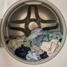 Damp clothes lying still at the bottom of an open dryer drum