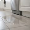 A puddle of water on a tiled kitchen floor in front of a dishwasher’s kick plate