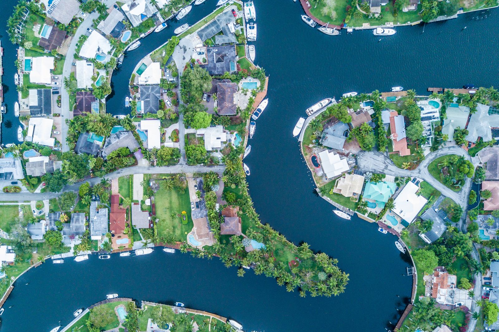 Looking straight down on the Tarpon River neighborhood of Fort Lauderdale: houses with pools on curving canals, boats tied up behind them