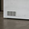 The ventilation grille low on the side of a white chest freezer