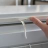 A fingertip lifting a split section of a freezer lid’s rubber seal