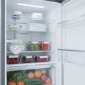 An appliance thermometer hanging from a shelf inside an open refrigerator