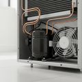 The compressor, copper tubing and condenser fan behind the rear access panel of a refrigerator