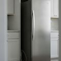 A stainless steel built-in refrigerator rolled forward out of its cabinet opening