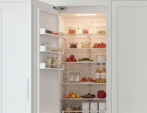 A white panel-ready column refrigerator standing open between matching cabinet panels, its shelves stocked with food