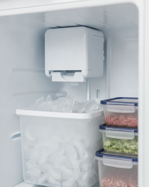 An ice maker high in a refrigerator’s freezer above a bin of crescent ice cubes