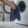 Hands lifting a dripping wet towel out of a front-load washer