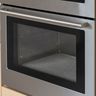 The closed glass door of a stainless steel wall oven