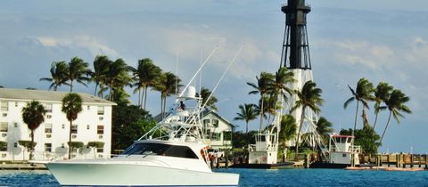 A sport-fishing boat in the Hillsboro Inlet, palms and the Hillsboro Inlet Light behind it