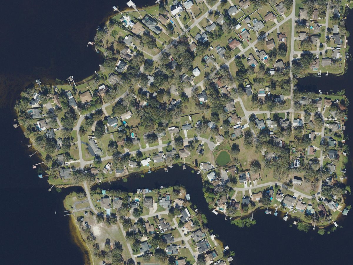 Homes with boat docks on a wooded point in Lake Padgett, Land O’ Lakes, seen from above