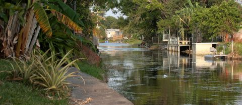 A residential canal in Margate lined with docks and trees, a small house at the far end