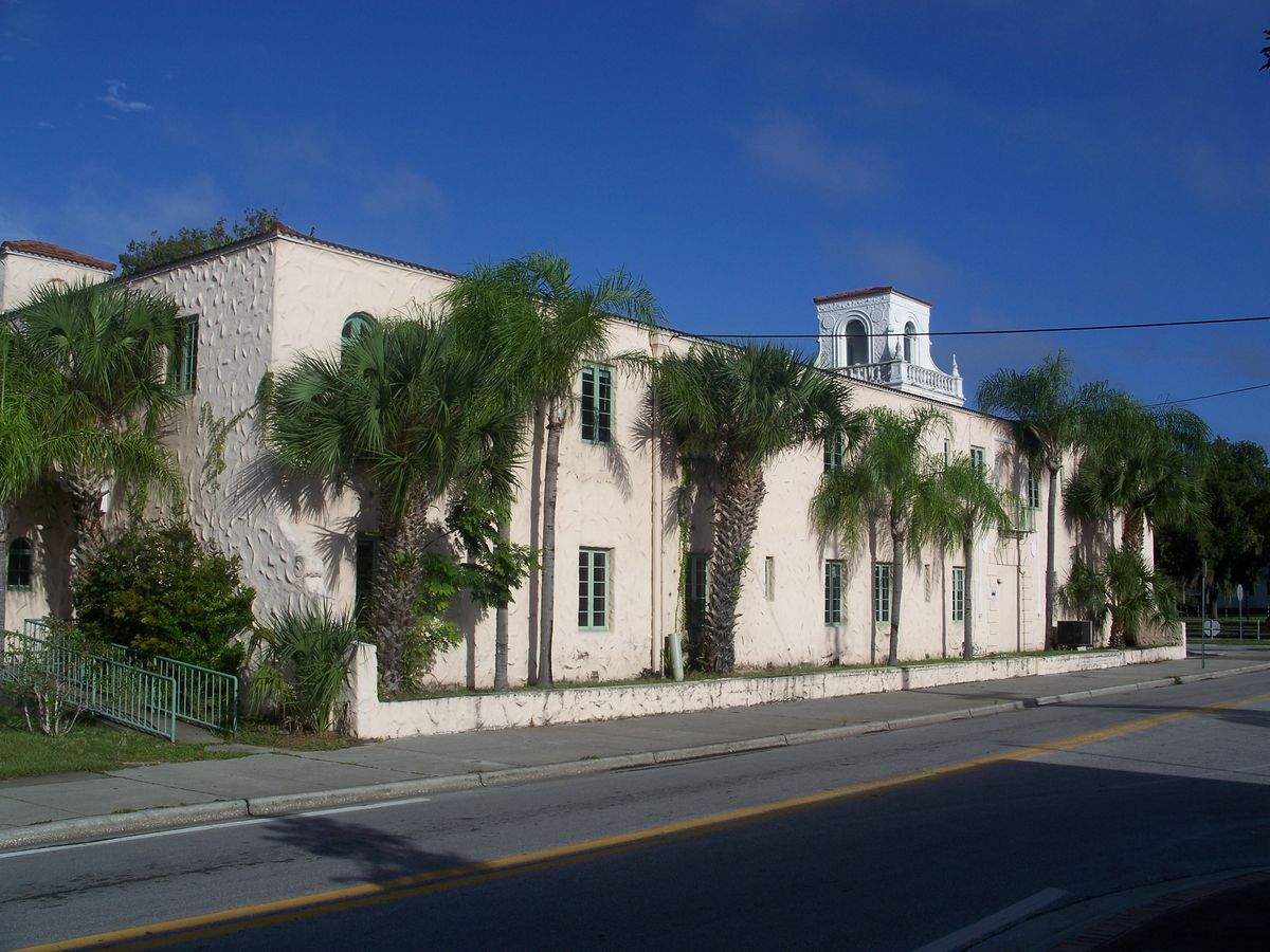 The Hacienda building on Main Street in New Port Richey, white stucco walls and a rooftop tower behind palms