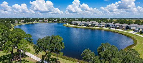 A blue lake with live oaks and a lakeside neighborhood under big white clouds