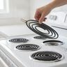 A hand lifting a coil element off a white electric range