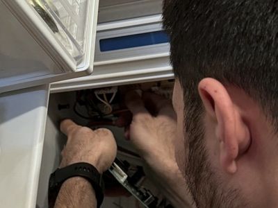 Hands at a control board behind a refrigerator’s inner panel