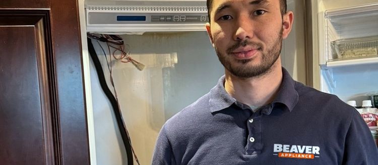 A technician in a Beaver Appliance polo in front of an open built-in refrigerator