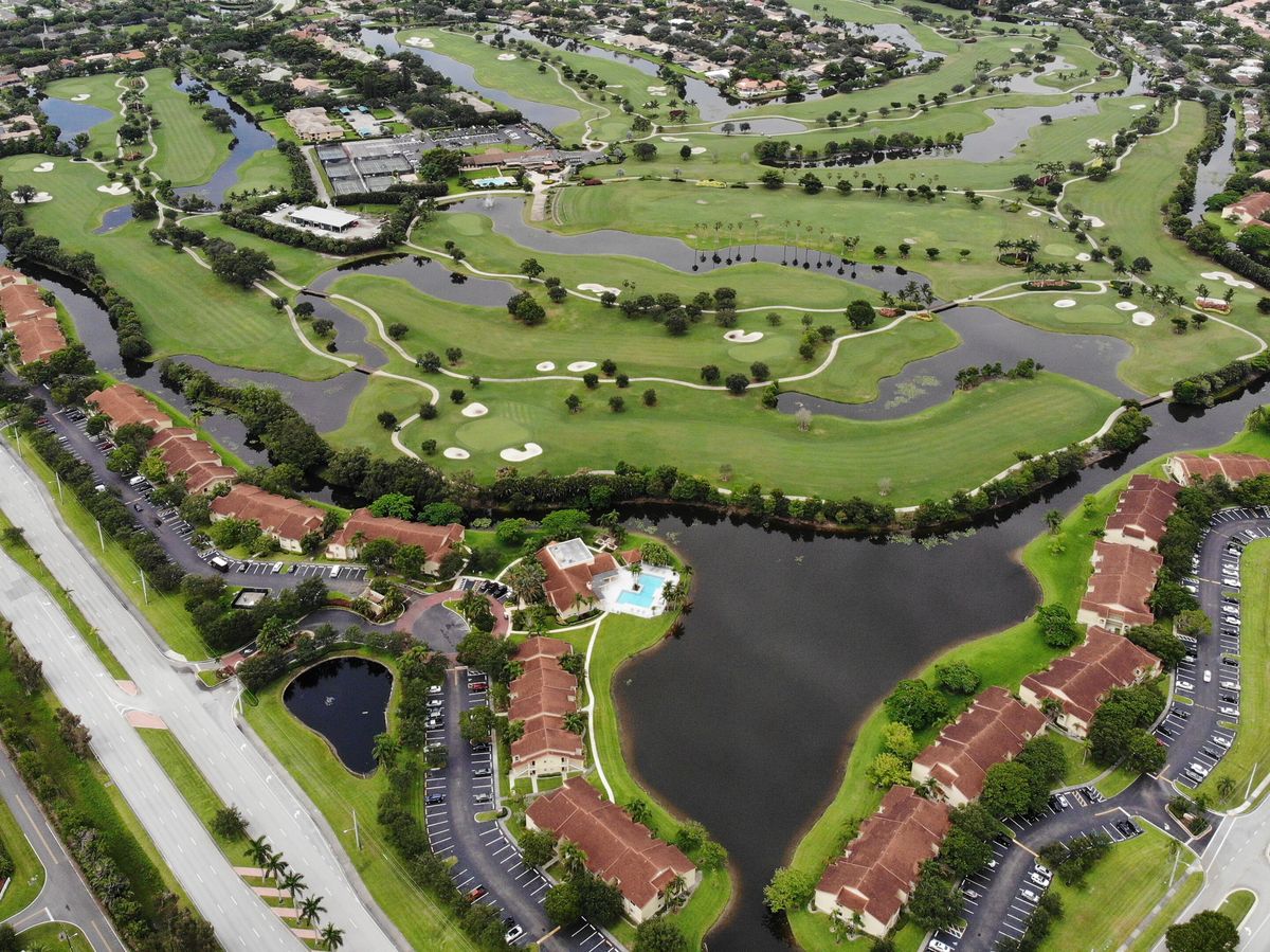 A golf course in Plantation from the air: fairways and lakes ringed by two-story condo buildings with tile roofs