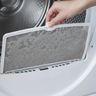 A hand lifting a lint screen, gray with lint, out of a dryer