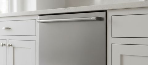 The top of a stainless dishwasher door and its bar handle, under a stone countertop