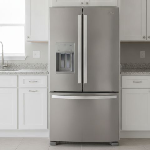 A stainless steel French door refrigerator between white kitchen cabinets