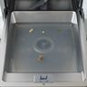 Cloudy water standing in the bottom of a dishwasher tub, with a few food scraps