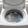 Gray water and clothes still standing in a washer drum after the cycle