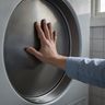 A hand pressed flat against the back of an empty dryer drum