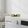 A spirit level lying on top of a white washing machine