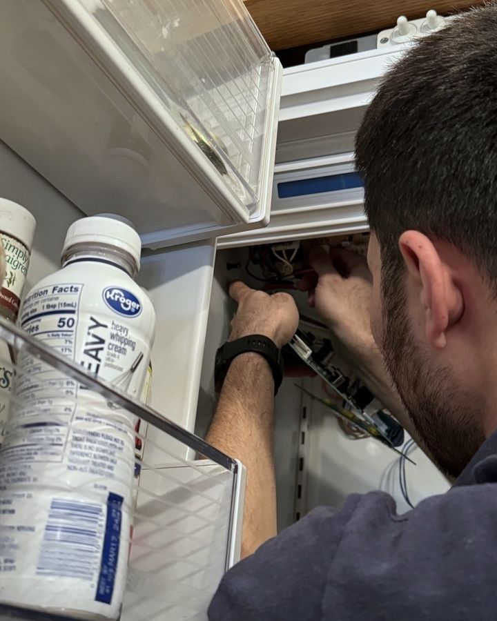 Hands at a control board behind a refrigerator’s inner panel, on a Beaver Appliance job