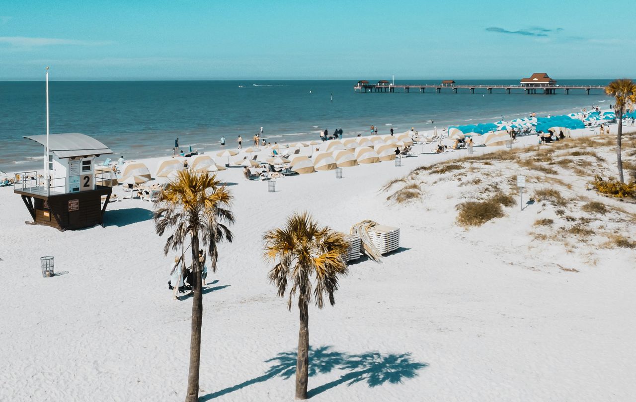 Palms and white sand on Clearwater Beach, a lifeguard stand and the pier reaching into the Gulf