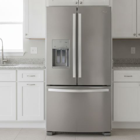A stainless steel French door refrigerator between white kitchen cabinets