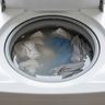 Gray water and clothes still standing in a washer drum after the cycle