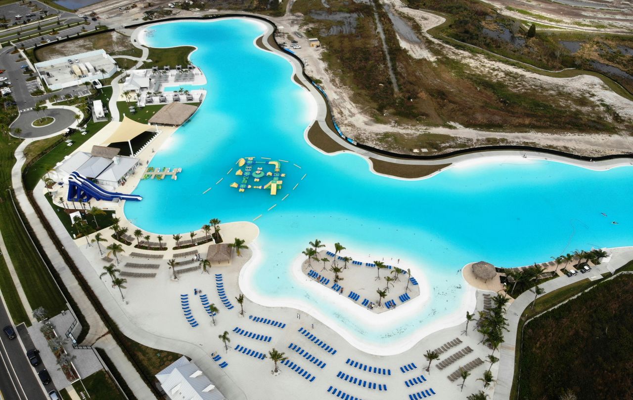 A turquoise lagoon with a white sand beach, palms and loungers in Wesley Chapel, seen from a drone