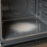 Fine pale ash on the floor of an empty oven, the racks taken out
