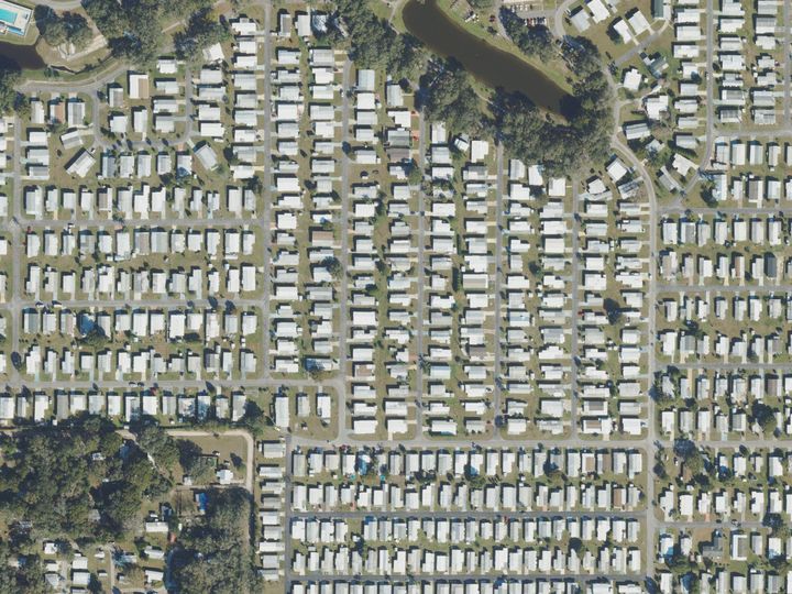 Rows of mobile homes on short streets around a lake in Zephyrhills West, seen from above